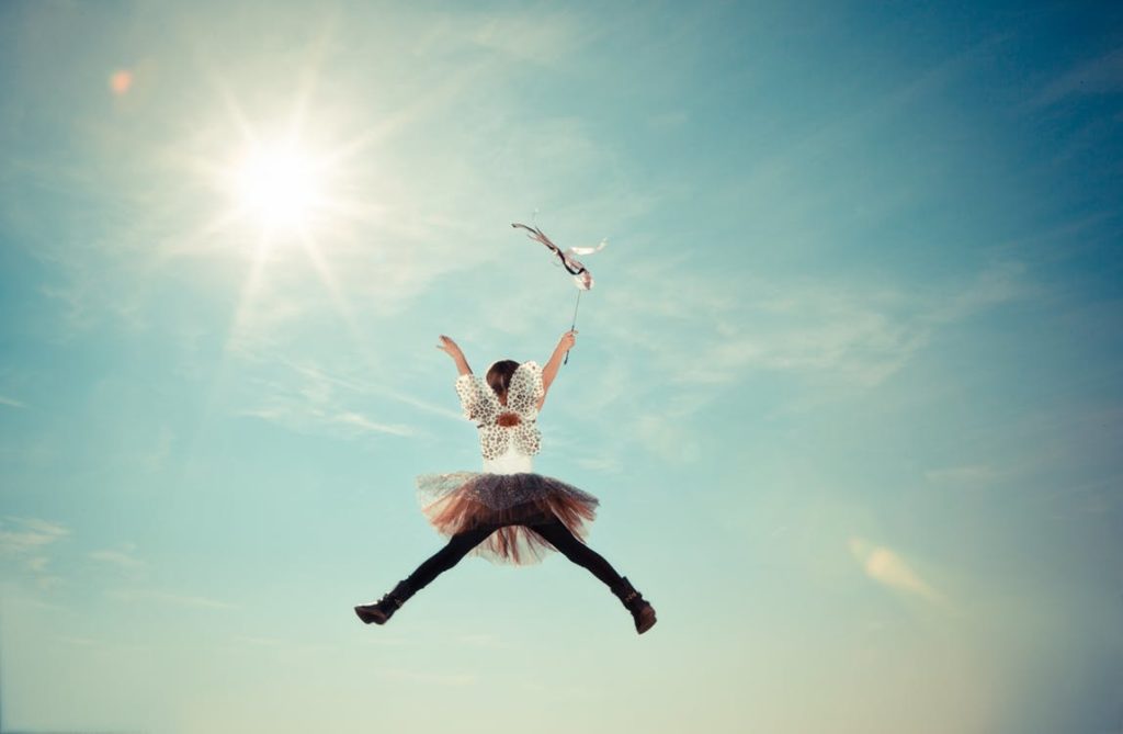 A girl jumping for joy with the sun rising in the background